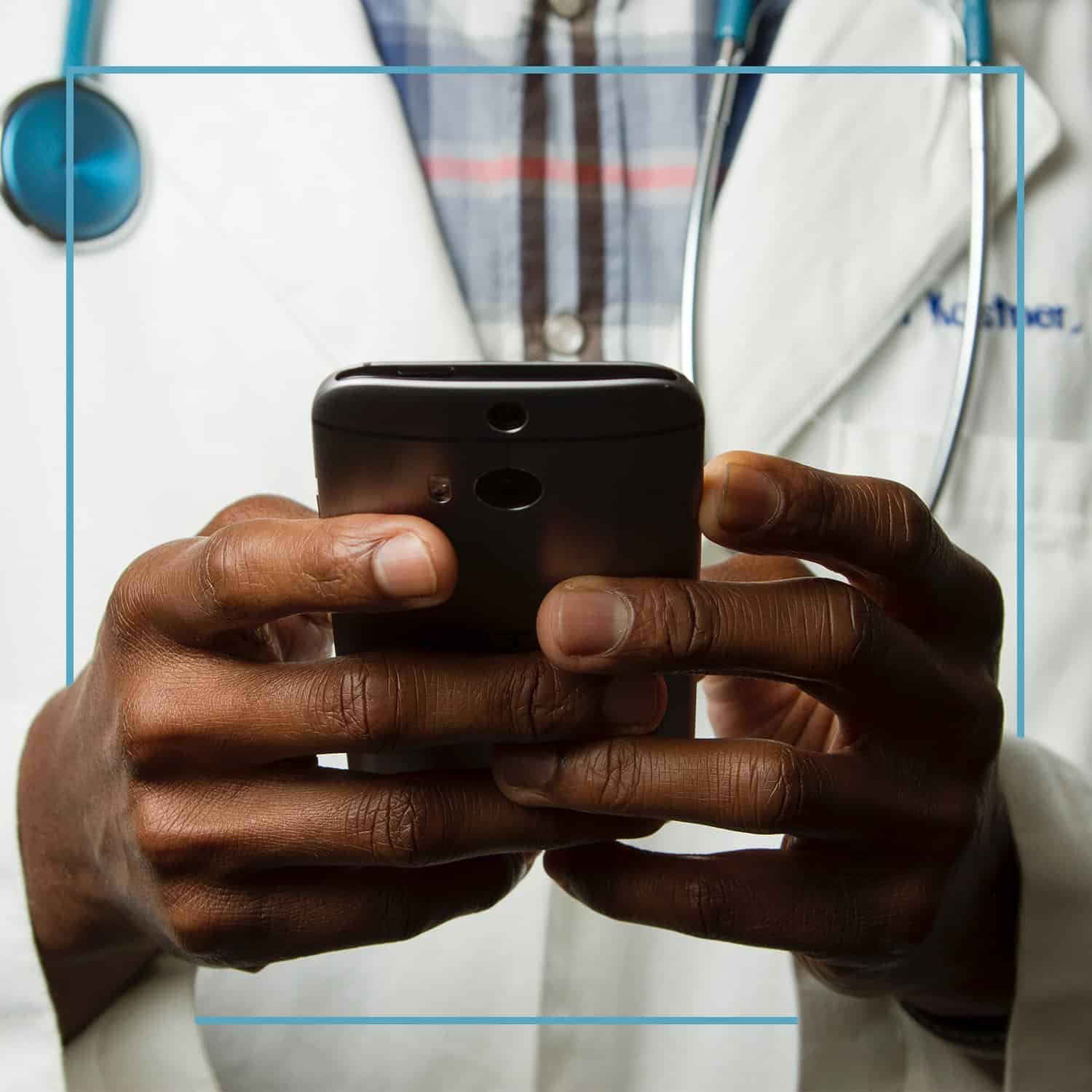 Doctor wearing a stethoscope looking at the screen on his phone